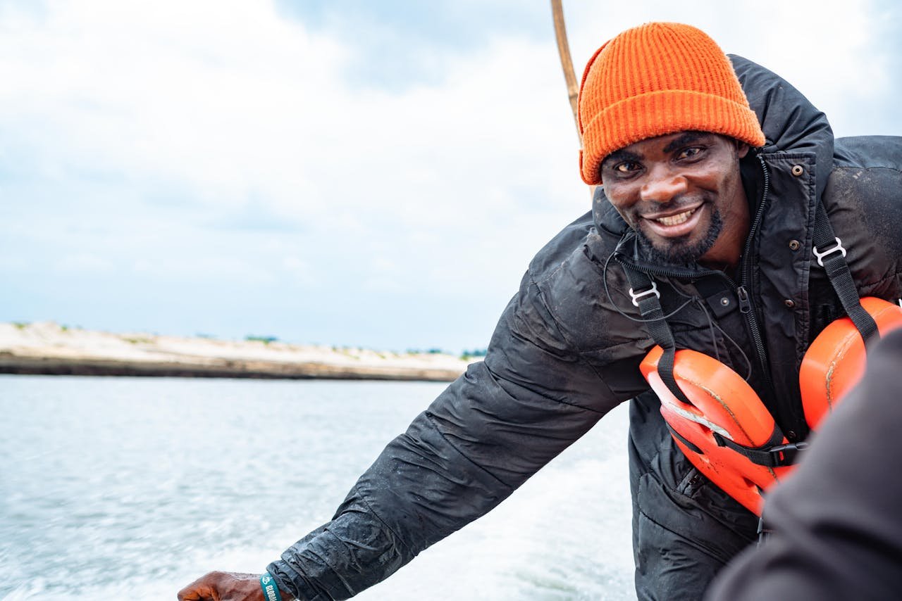 Smiling man wearing an orange hat and life jacket on a boat in Port Harcourt, Nigeria.
