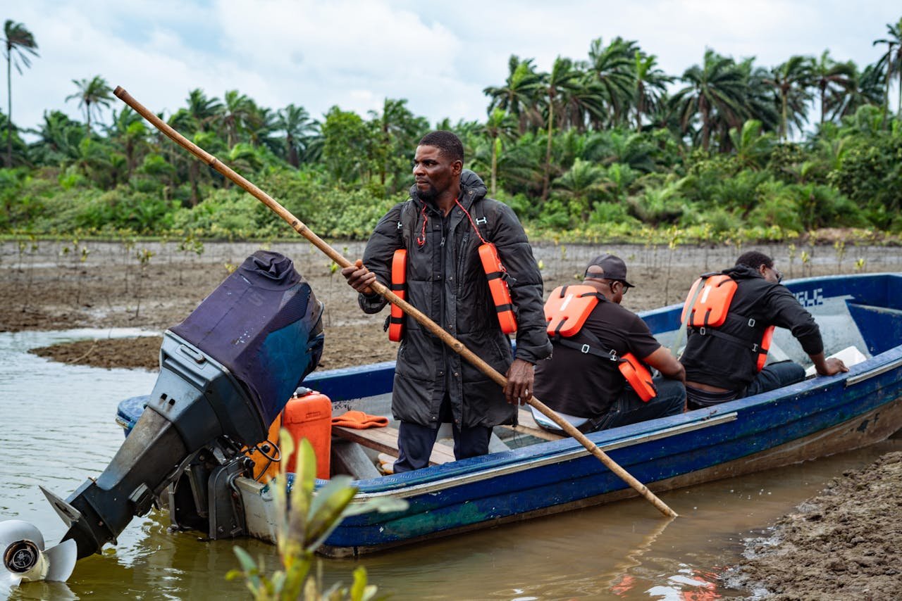 Fishermen in a motorized boat navigating a river, wearing life jackets, in Port Harcourt, Nigeria.
